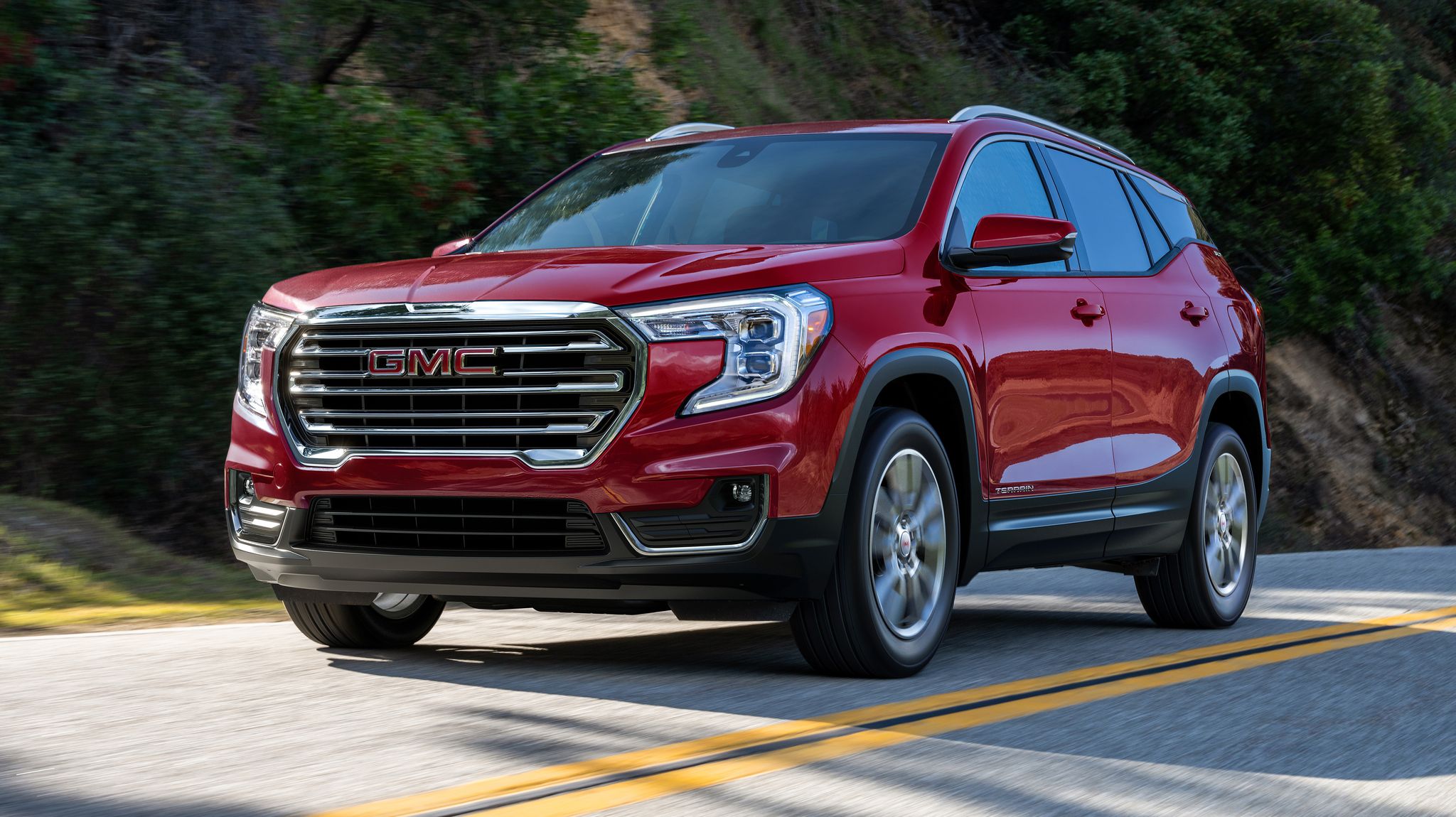 a 2023 gmc terrain in red driving on a highway