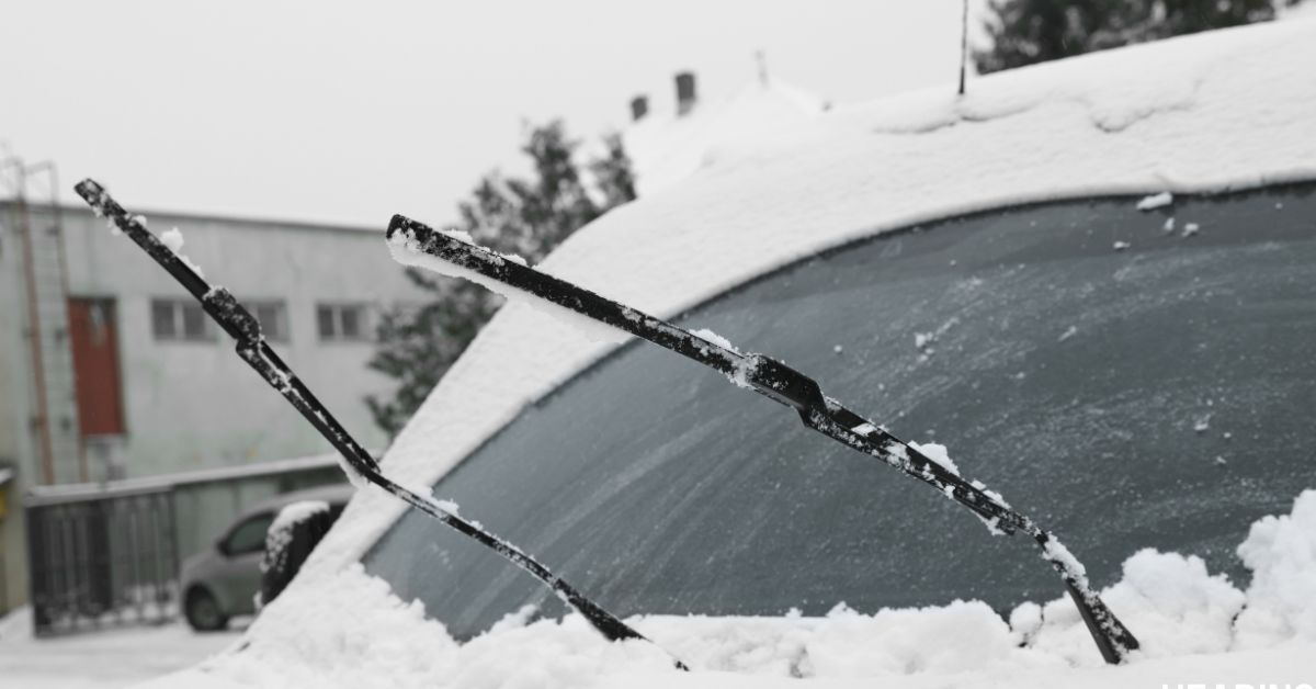 a car with snow all over it, and the windshielf wipers lifted up