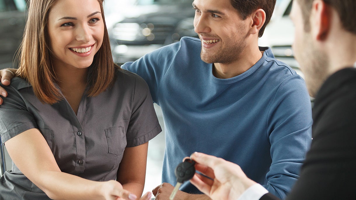 a man looking at a young woman in a dealership with a salesman